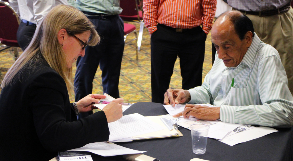 An unnamed buyer (right) signs paperwork after winning the auction for the Economy Inn. Photo by Michael Thompson.